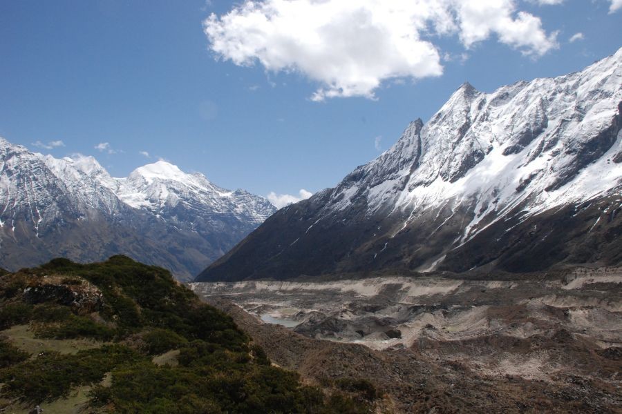Manaslu Circuit trek trail with snow-capped peaks and traditional stone cairns under clear blue skies
